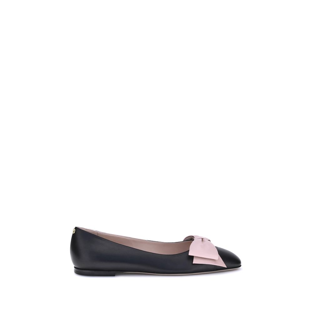 Black ballet flat with a pink bow on a white background