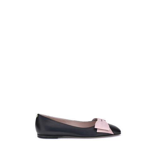 Black ballet flat with a pink bow on a white background