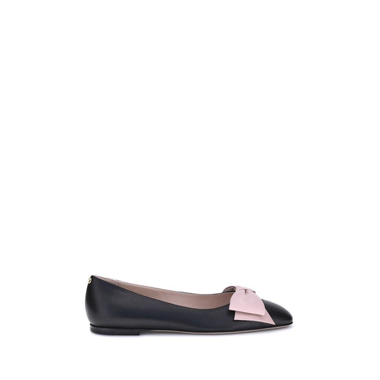 Black ballet flat with a pink bow on a white background